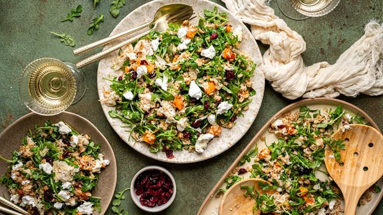 Butternut Squash and Farro Salad shown served on plates, being enjoyed with extra cranberries and wine.