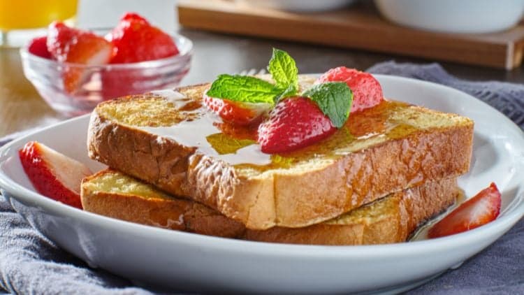 Brioche French Toast made with St. Pierre Brioche Slices served on a plate and topped with Driscoll's Strawberries.
