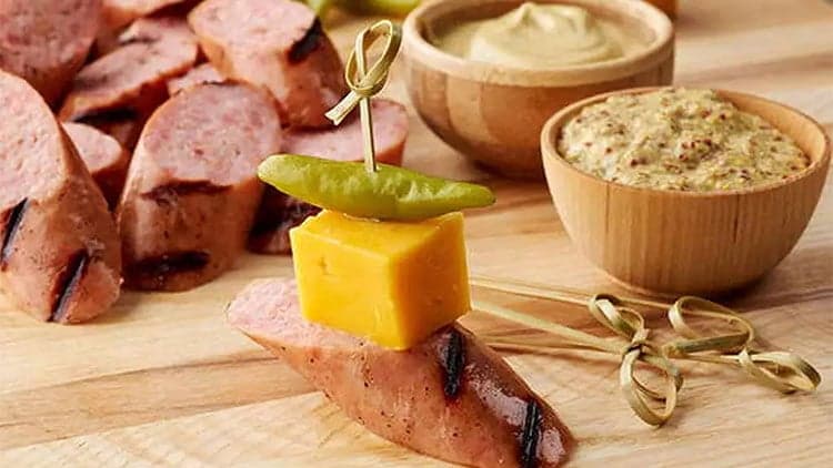 A Coleman Jalapeño Cheddar Brat Bite assembled on a toothpick and ready to be enjoyed.