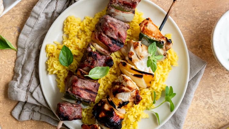Beef and chicken EZ Meals Kebobs from Dierbergs grilled and served on a plate with saffron rice and yogurt sauce.