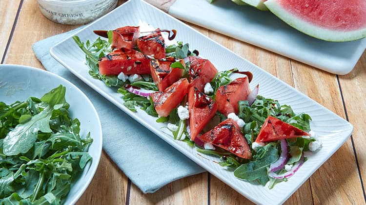 Grilled Watermelon Salad with Arugula and Goat Cheese shown on a platter, ready to be served and enjoyed.