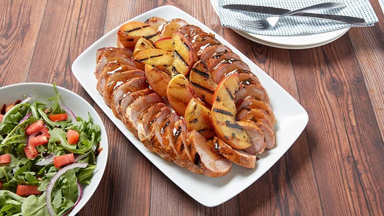 Bourbon Glazed Pork Tenderloin with Grilled Local Peaches shown on a platter, ready to be served and enjoyed.